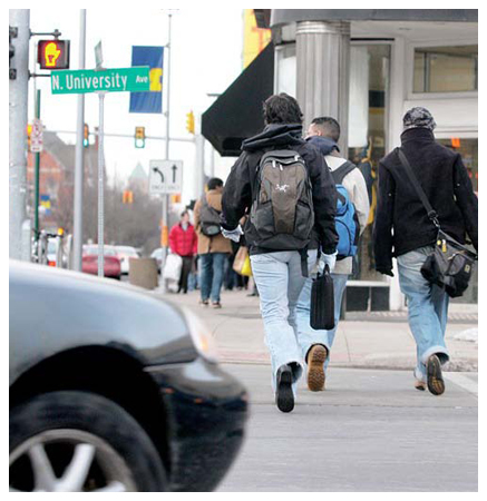 Pedestrians walking against a solid Don't Walk signal.